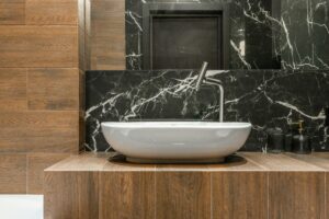 Elegant bathroom with a modern washbasin, wood paneling, and black marble decor.