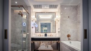 Elegant bathroom featuring a marble sink, bathtub, and mirror with ambient lighting.